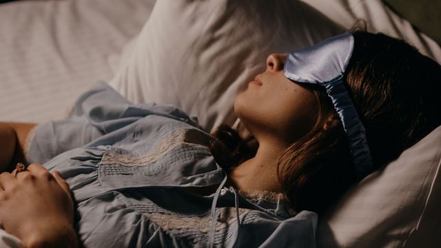 Girl sleeping in bed with a sleep mask. 