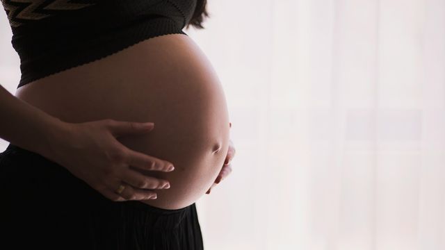 Pregnant woman gently holding her baby bump. 