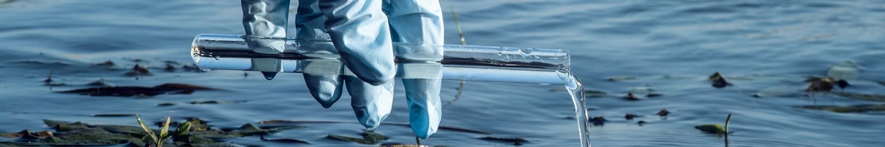 Gloved hand collecting a water sample for PFAS testing. 