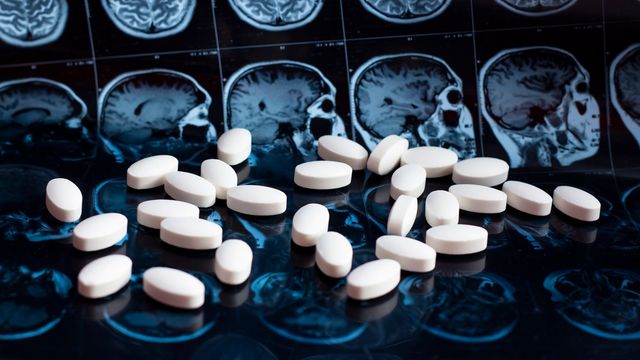 White pills scattered across a series of black and white brain scans. 