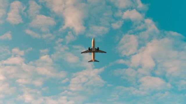 Commercial airplane flying overhead against a blue sky filled with clouds. 