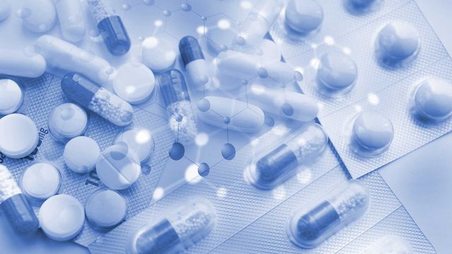 Assorted tablets and capsules in blister packs with molecular graphics, representing drug repurposing research. 