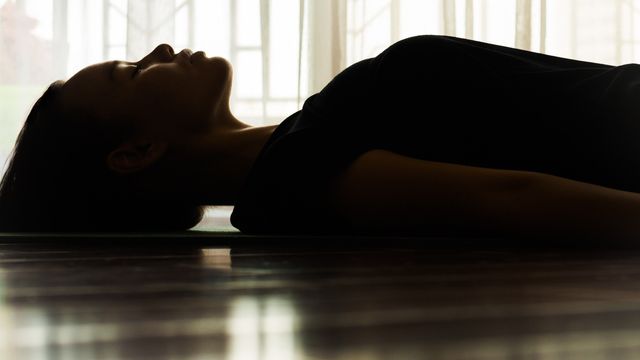 Silhouette of a person lying on a floor near a window, representing a psychedelics-themed wellness concept. 