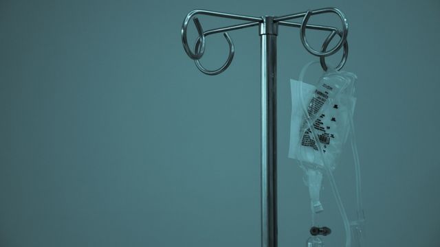 IV drip bag hanging from a metal stand in a clinical setting. 