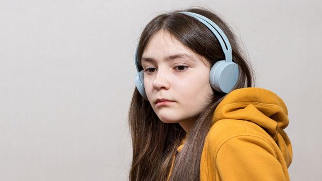 Person wearing over-ear headphones and a yellow hoodie, representing autism-related sensory accommodation. 