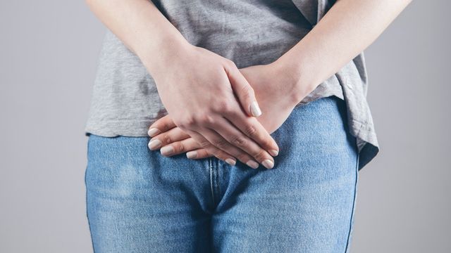 Woman holding her lower abdomen, illustrating urinary tract infection symptoms. 