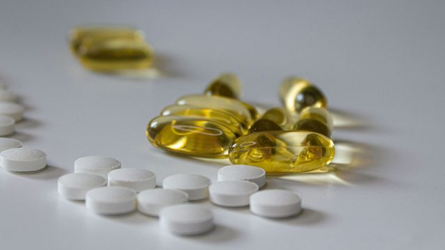 Vitamin supplements and white pills on a flat white surface. 