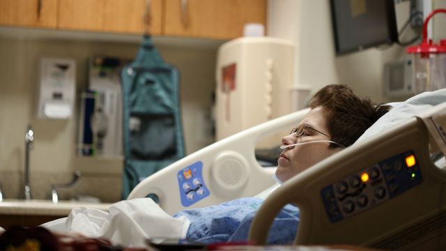 Patient lying in a hospital bed receiving oxygen through a nasal cannula. 