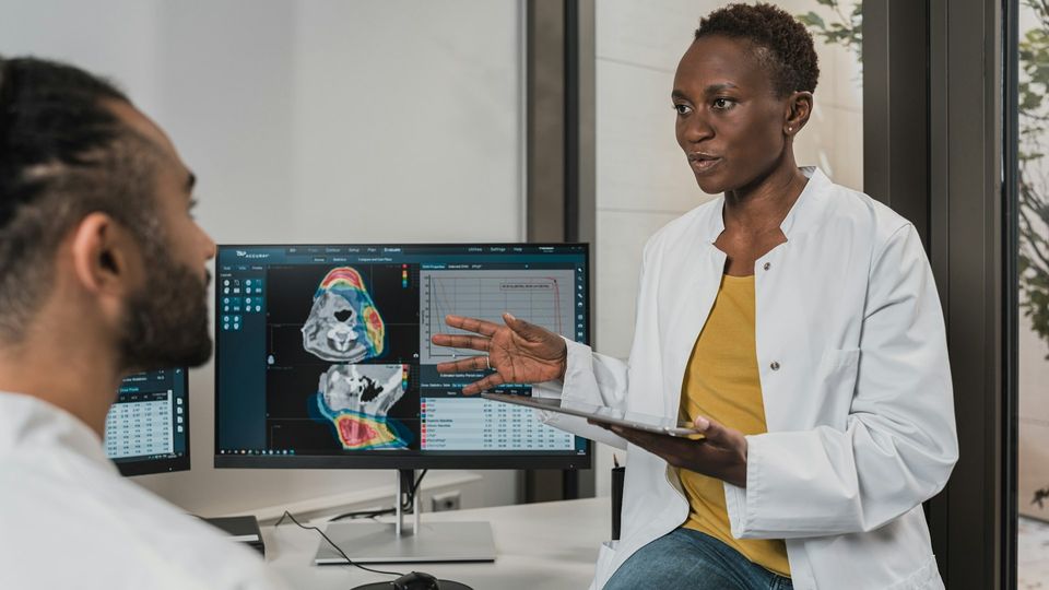 Doctors discussing medical imaging results on a computer monitor in a clinical setting.