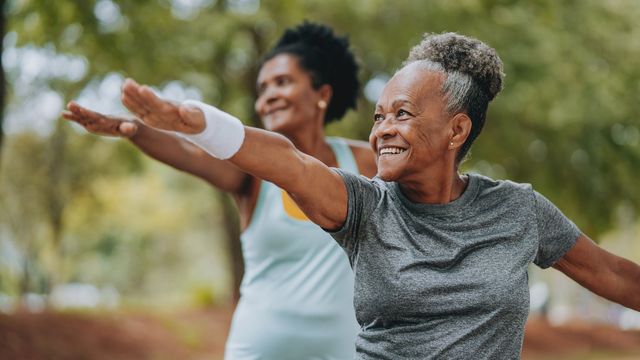 Adults exercising outdoors with arms extended, promoting healthy aging and mobility. 