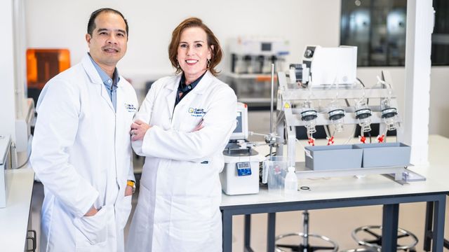 Two scientists in lab coats standing in a modern research laboratory. 