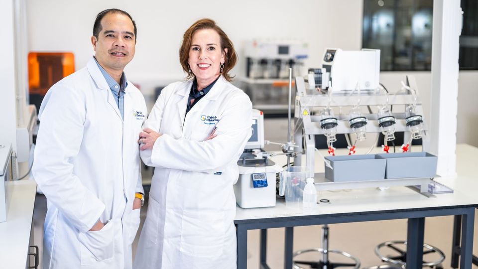 Two scientists in lab coats standing in a modern research laboratory.