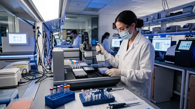 AI-generated image of a scientist operating automated liquid-handling equipment during NGS library preparation in a modern genomics laboratory. 