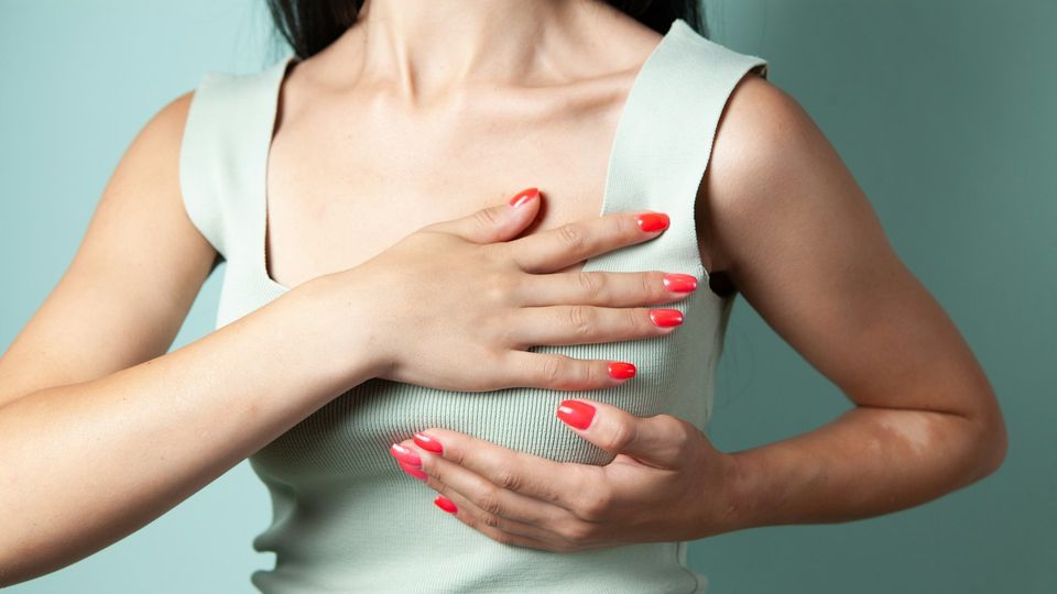 Woman performing a breast self-examination for breast health awareness.