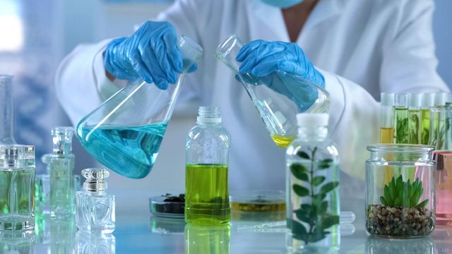 Scientist handling chemical flasks for sustainable SVOC analysis and automated extraction. 