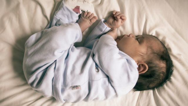 Newborn baby sleeping peacefully on a bed. 