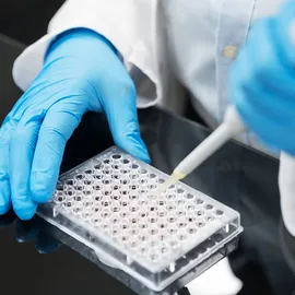 Researcher pipetting samples into a microplate for microbial quality control testing.