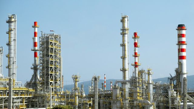 Industrial refinery complex with tall processing towers, pipes, and equipment. 