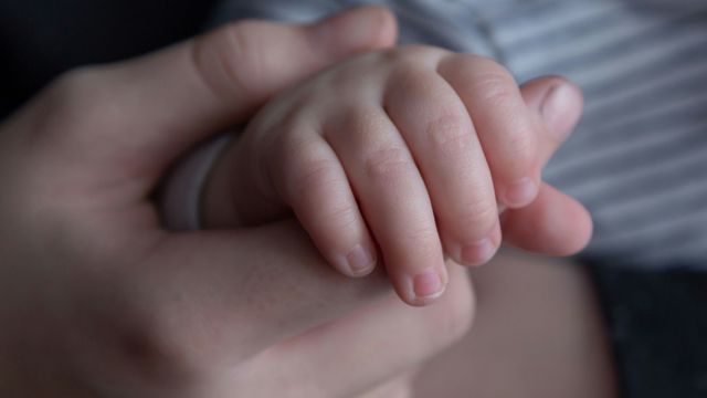 A parent holding a baby's hand. 