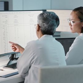 Two researchers observe data on a monitor in a laboratory. 
