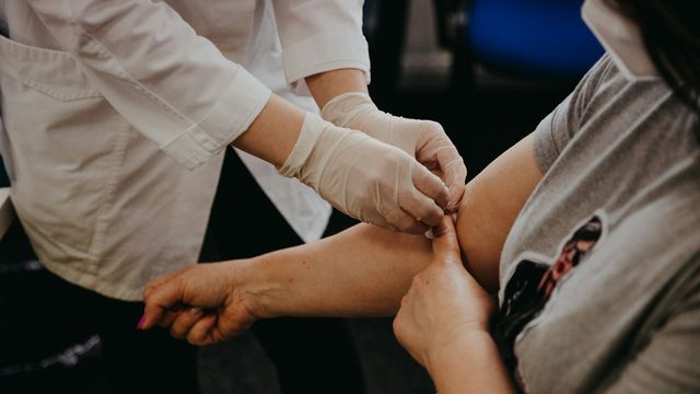 A health worker applying a bandage or swab to a patient's arm after a procedure. 