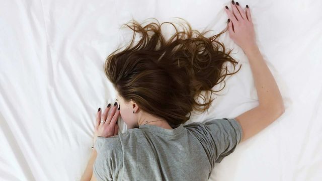 A woman lying face down on a bed while resting. 
