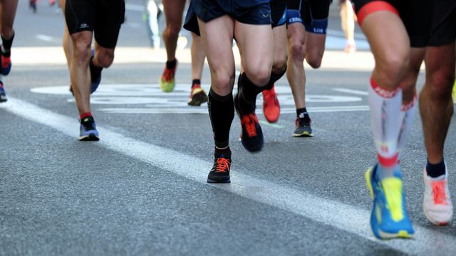 A photo focusing on the legs of runners in a race, as they run close to the camera. 