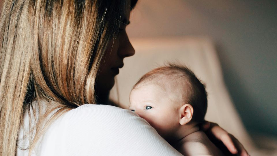 Close-up of a female holding a newborn baby on her chest.