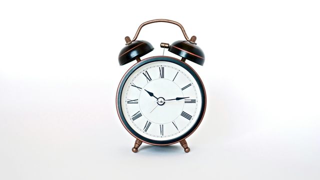 Vintage alarm clock showing 10:15 on a white background. 