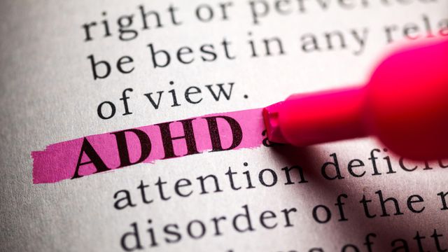 ADHD acronym highlighted in pink marker on a printed page discussing attention deficit disorder. 