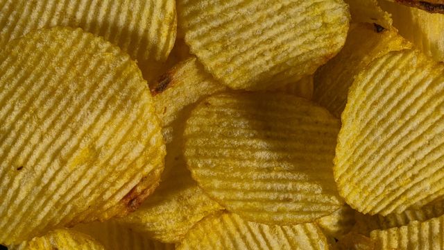 A close up photography of ruffle-cut flavored chips in a bag. 