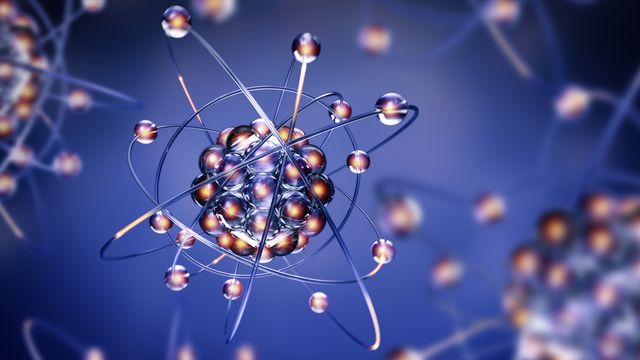 A digital illustration of an atom floating in blue space, with a background of blurred additional atoms. 