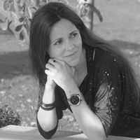 Black and white portrait of Kim P.C. Kuypers seated outdoors, looking thoughtfully to the side.