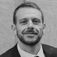 A headshot of Dr. Jesse Gordon-Blake in greyscale.