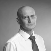 Portrait of a professor in a white shirt and tie against a plain background.