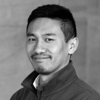 Portrait of a smiling male lecturer in a collared shirt and jacket.