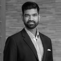 Professional black-and-white portrait of a CEO in a suit standing against a modern background.