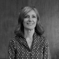 Black and white professional headshot of a woman smiling in front of a wooden background.
