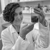 Black-and-white headshot of a lab researcher holding a soil sample.