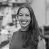 A black and white image of Sottile, smiling at the camera. She has long brown hair swept over one shoulder, and is standing in her lab.